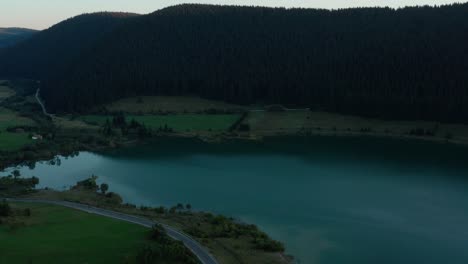 Drone-Volando-Hacia-Aguas-Azules-Tranquilas-En-La-Presa-De-Frumoasa-En-Rumania,-Inclinación-Aérea-Hacia-Abajo