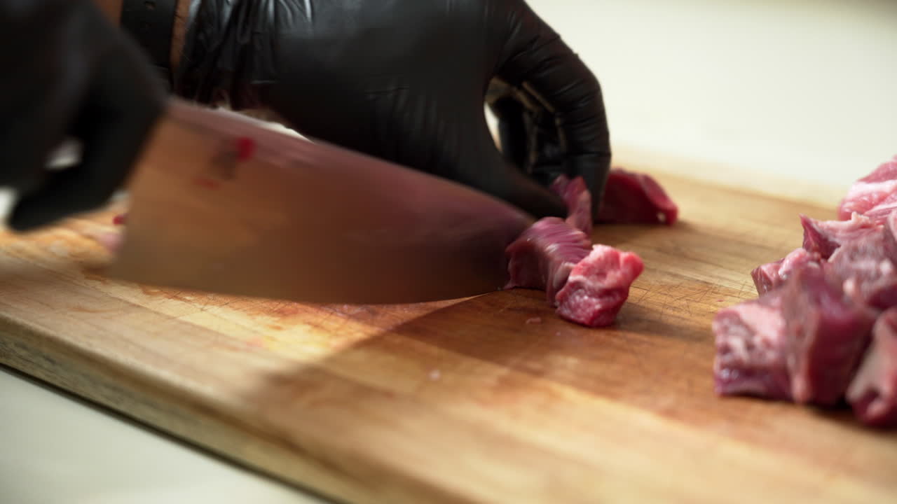 Chef is dicing the most delicious fresh chuck of beef, using black gloves and sharp chef knife