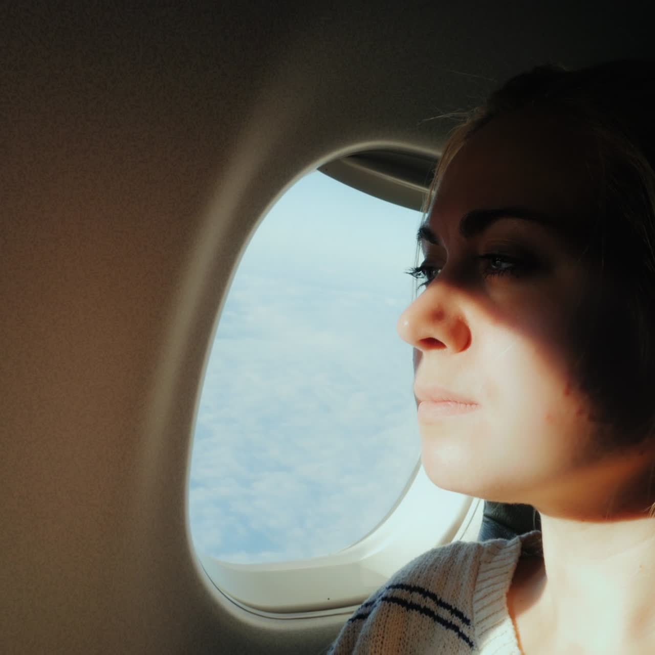 한 여성 승객이 비행기 창밖으로 1시 아래 도시를 내다본다