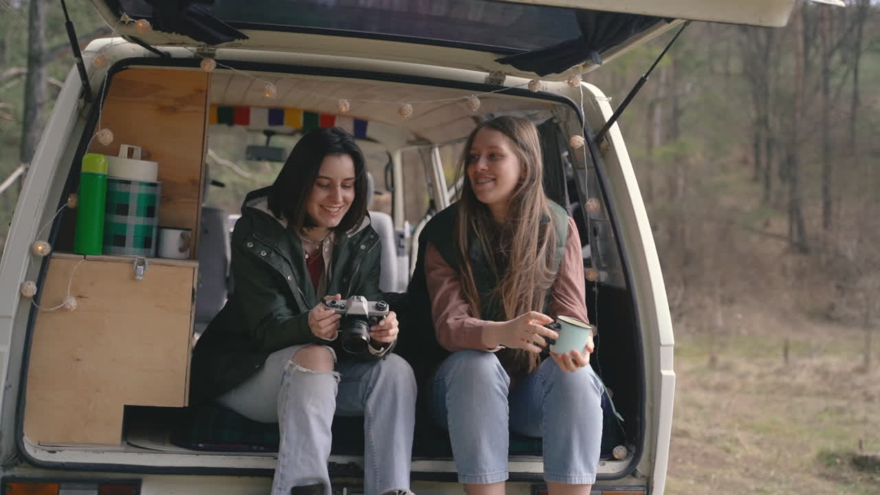 두 어린 여자 친구가 숲 한가운데 캐러밴 뒤에서 잡담을 한다