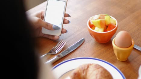 Frau-Benutzt-Mobiltelefon-Beim-Frühstück