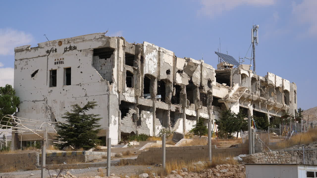 Carrellata all'indietro che mostra un hotel distrutto da bombardamenti di artiglieria appena fuori Homs, Siria