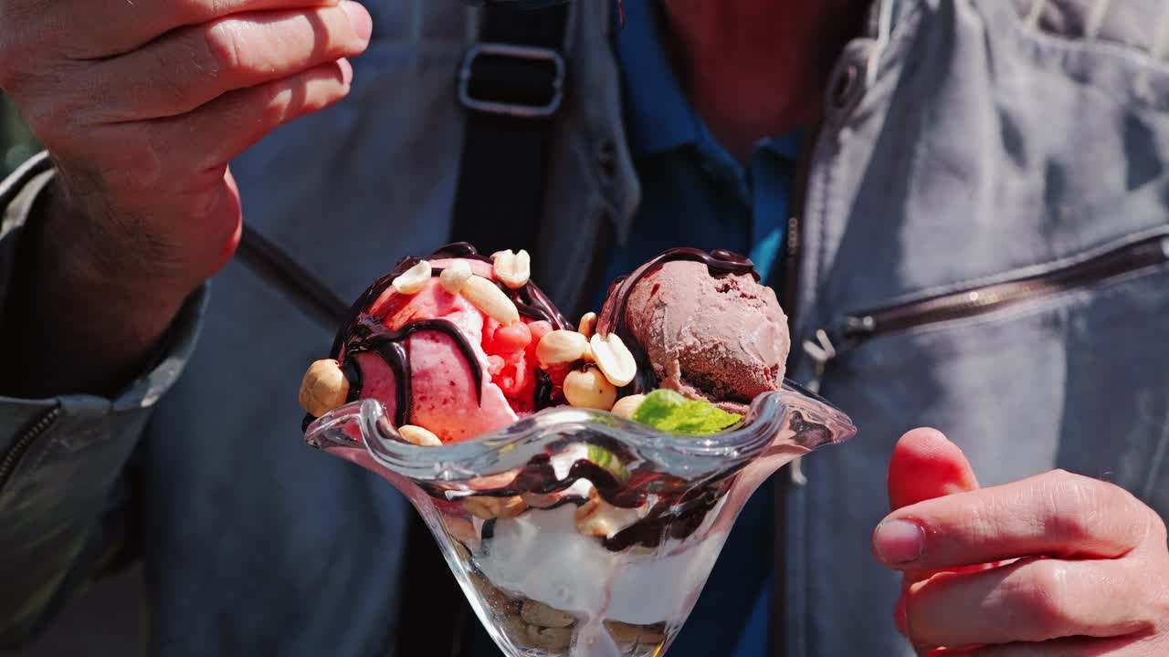 Slow motion close up of elderly man eating ice cream with chocolate and nuts