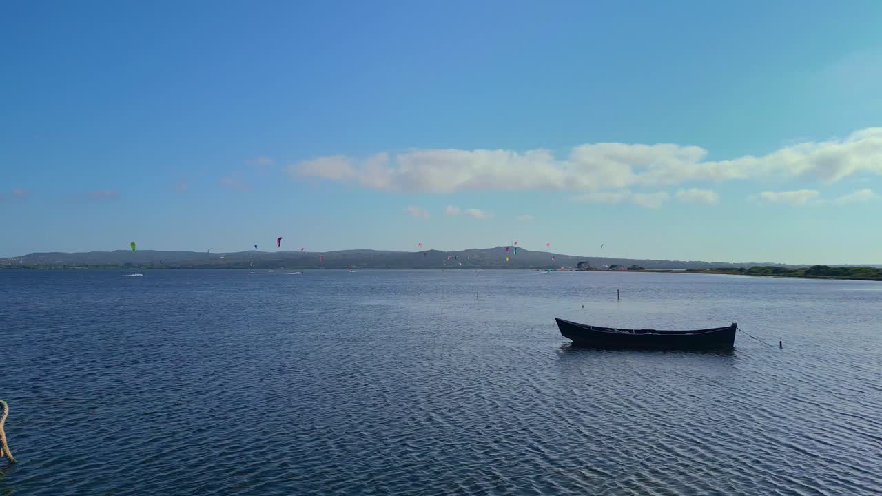 멀리 떨어진 카이트 서퍼들이 사르데니아 남쪽 지방에서 바다 물을 즐기고 있습니다.