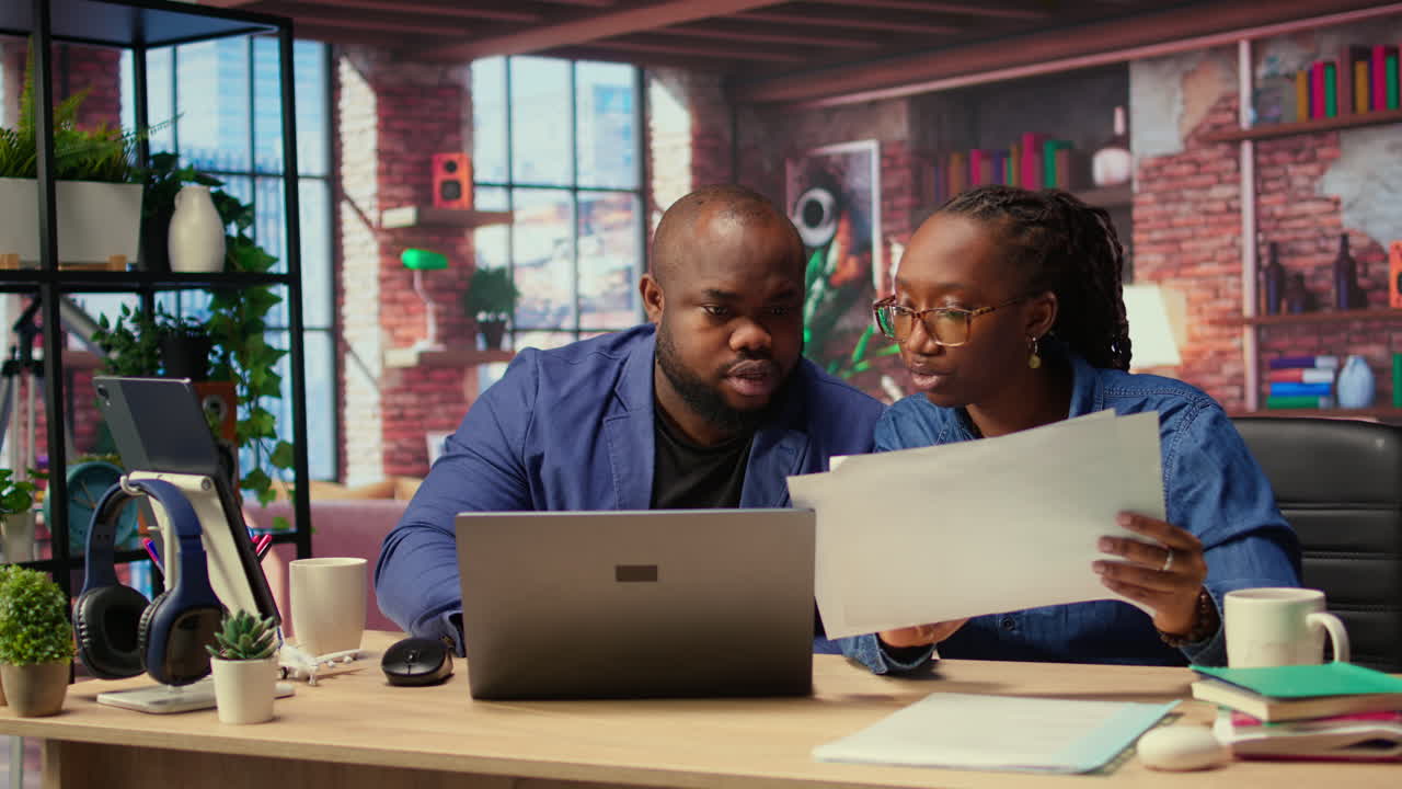 Young couple evaluating monthly reports numbers with a laptop and papers