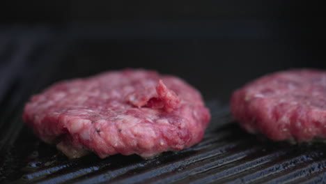 stationary extreme close up of burger patties sizzling on a bbq
