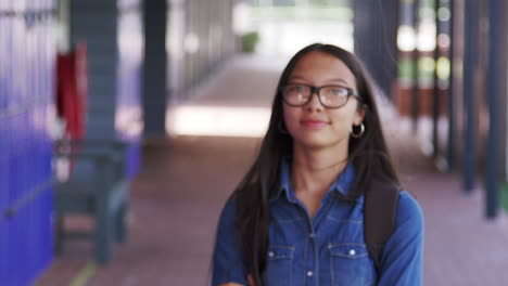 asian teenage girl walks into focus in high school corridor