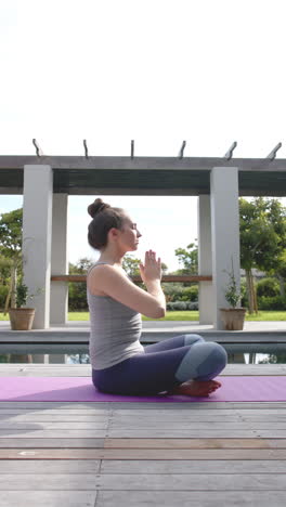 mujer caucásica centrada meditando en un tapete de yoga en el jardín en cámara lenta