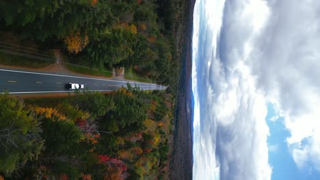 large semi truck transporting cargo across new hampshire mountains during fall season, vertical