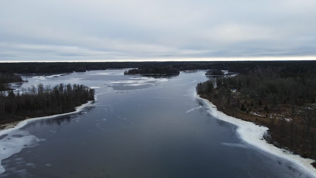 Jib-nosto kauniista järvestä talvella, metsän ympäröimänä Ruotsin maaseudulla pilvisenä päivänä.