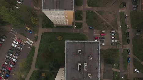roofs of blocks on a communist housing estate in central europe, with parking lots filled with cars, lawns, and trees