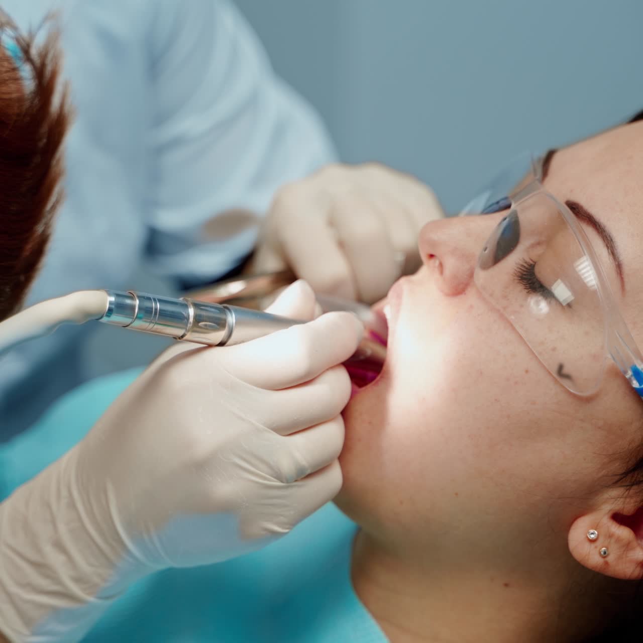. Dentist working with patient. Female dentist in uniform and gloves using dental instruments