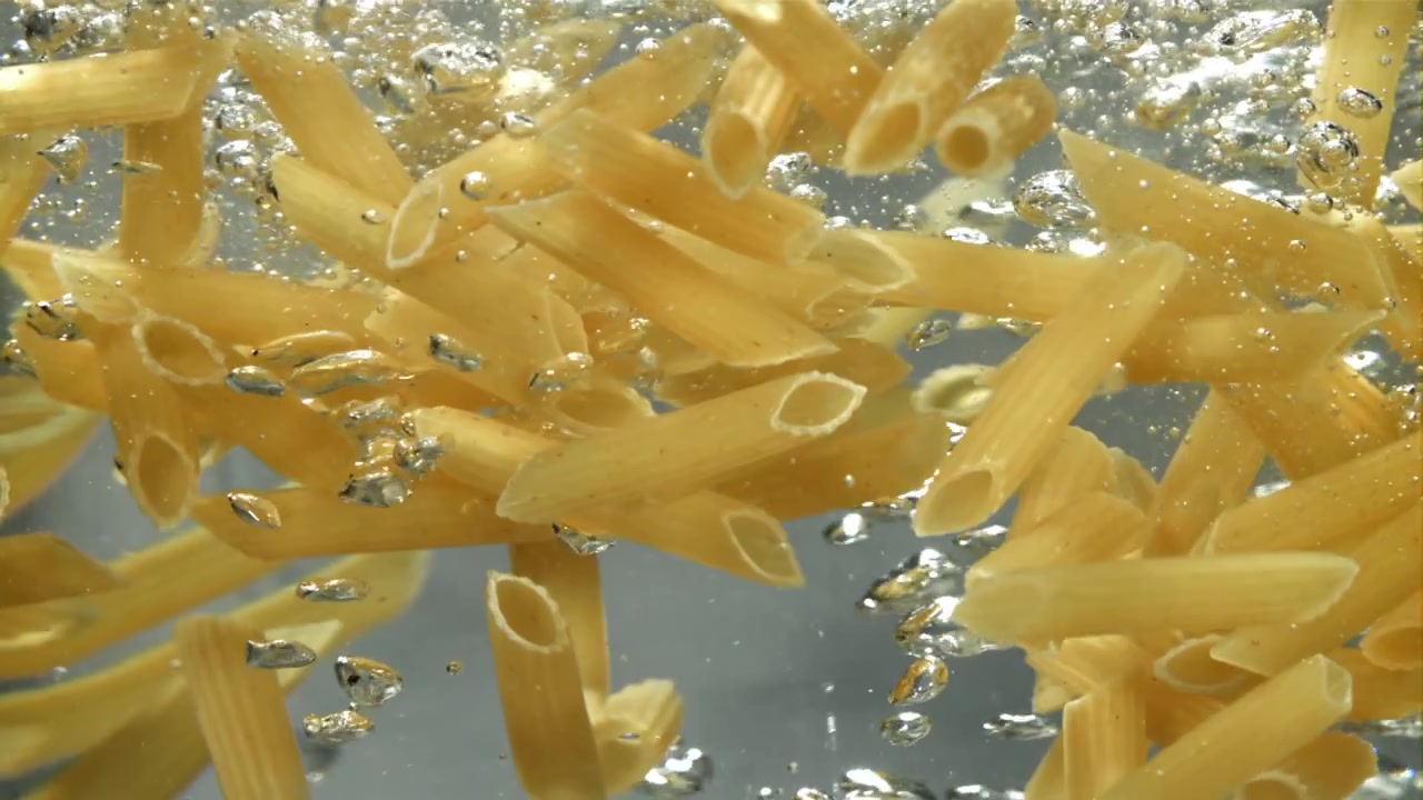 Primo piano di penne che bollono in acqua calda
