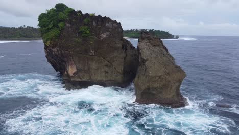 whitewash of powerful ocean waves eroding coastal rock outcrops forming a sea stack