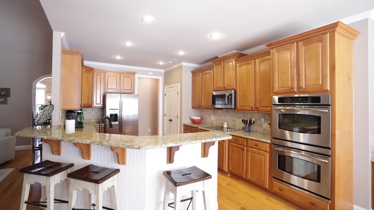 Large Brown U-Shaped Kitchen With Wood Cabinets And Marble Countertop