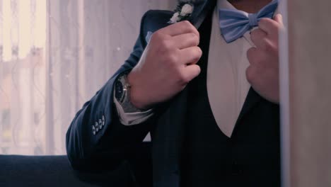 static shot of a groom in the mirror getting his suit ready before a wedding