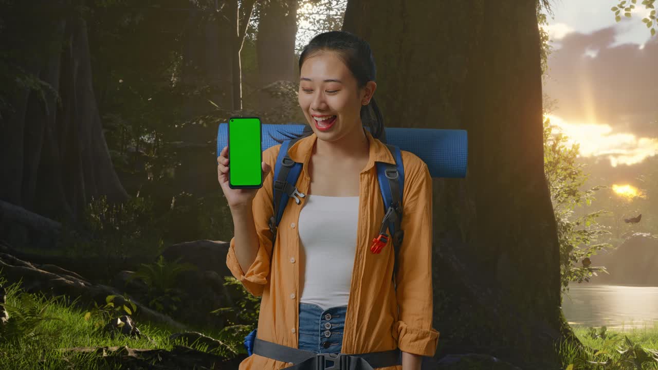 mujer mostrando teléfono de pantalla verde en el bosque