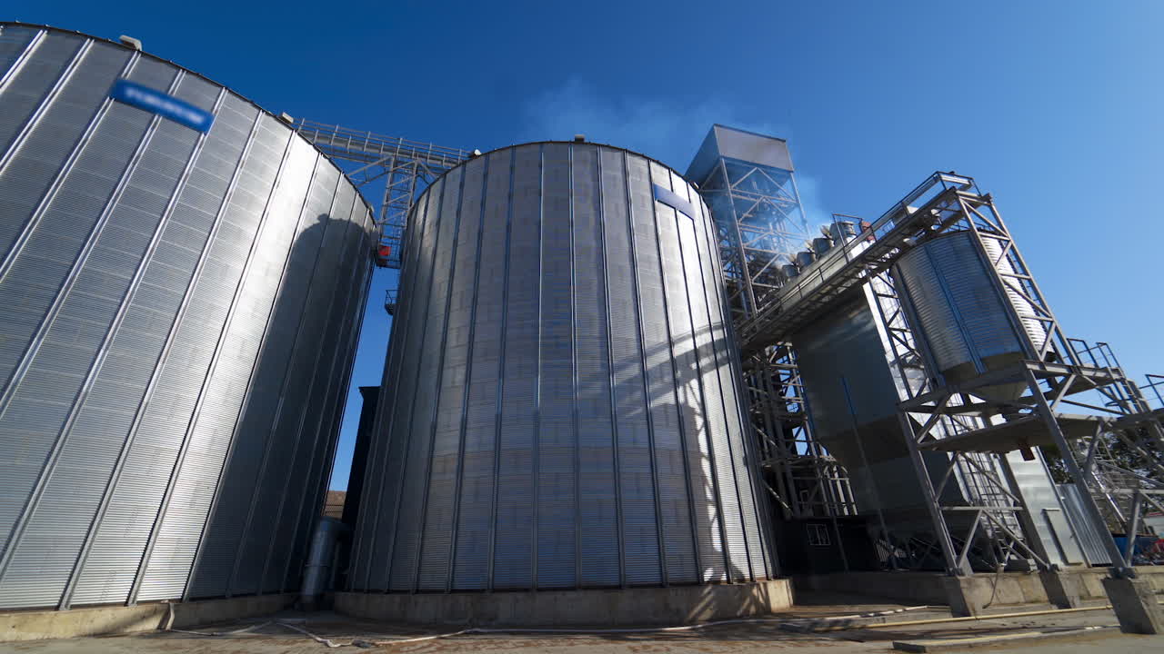 Exterior of grain elevators on field. Large granary of a modern industrial plant for agriculture. Industrial complex for storage crop.