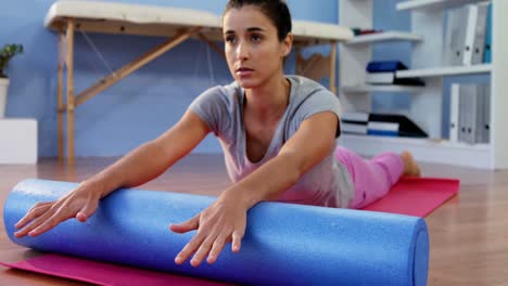 Physiotherapist-assisting-woman-while-exercising-on-exercise-mat