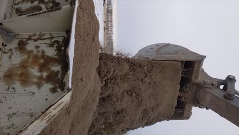 excavadora descargando un balde lleno de arena en la parte trasera de un camión de rocas ya cargado