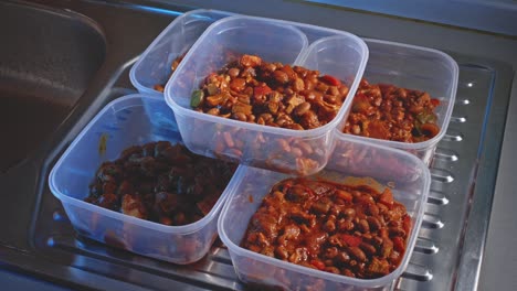 cooked spicy chicken beans divided into five containers for storing