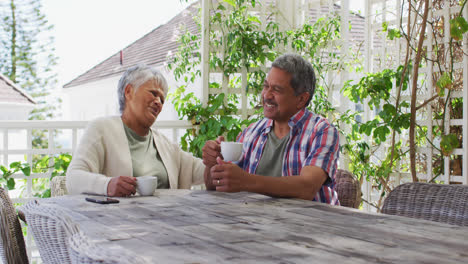 Feliz-Pareja-De-Raza-Mixta-Senior-Tomando-Un-Café-Hablando-En-El-Jardín