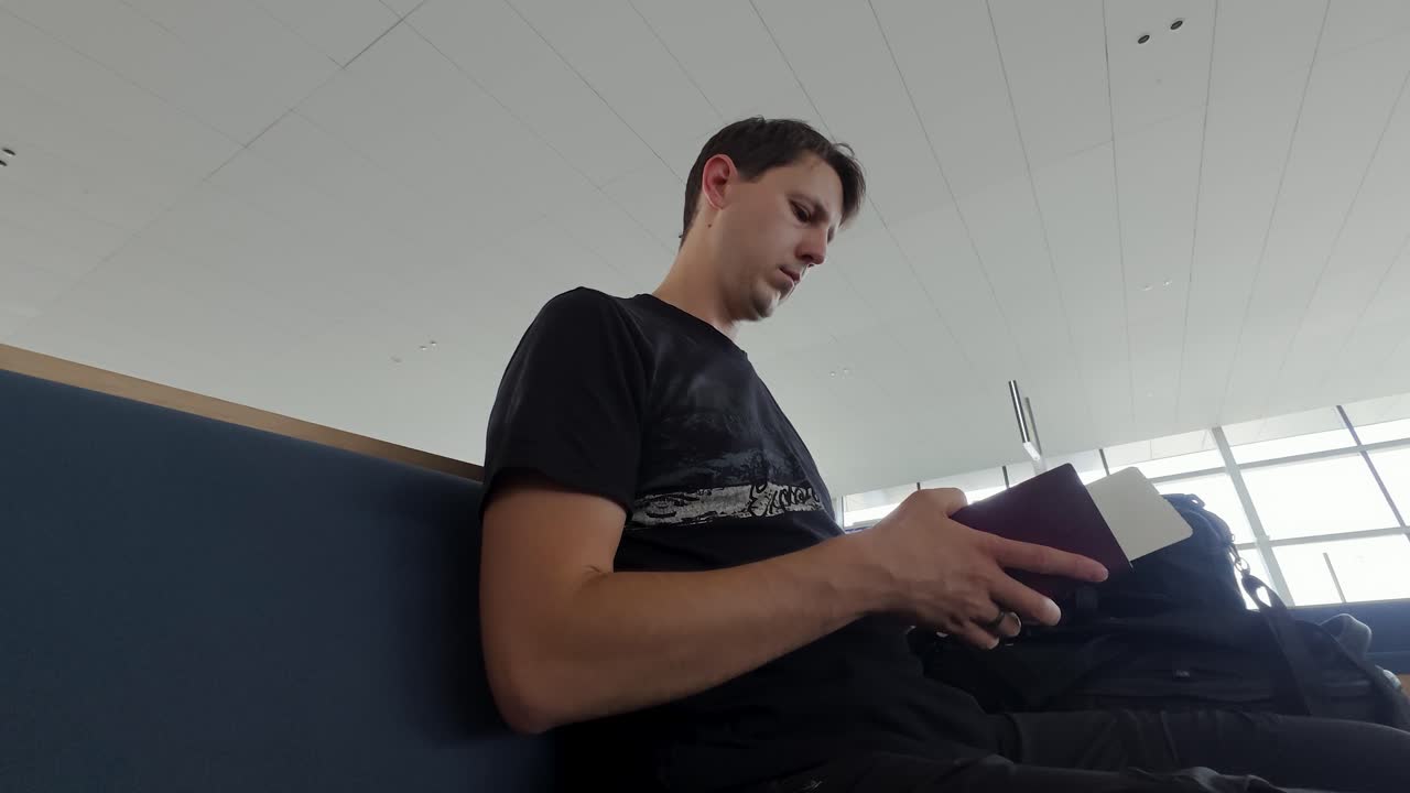 Viajante caucasiano do sexo masculino segura passaporte e cartão de embarque no lounge do aeroporto