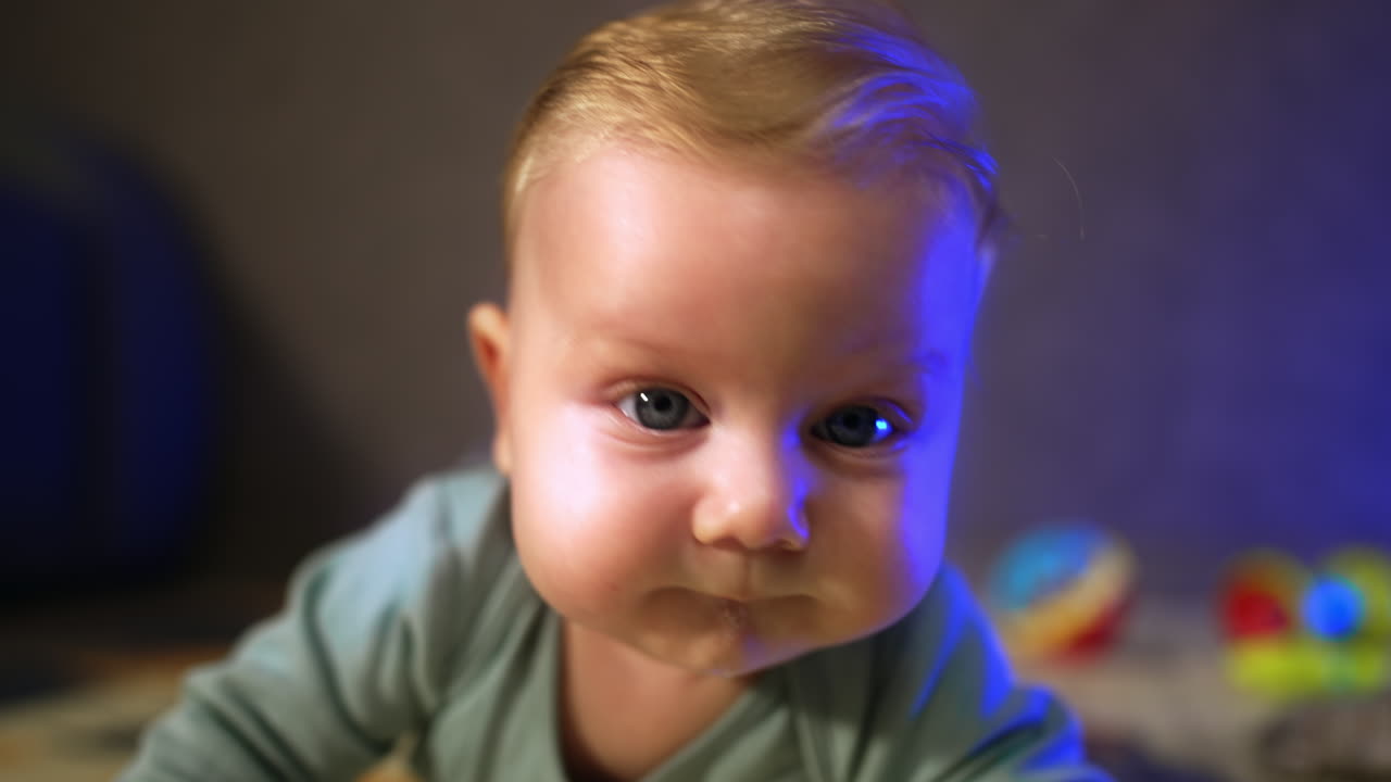 Beautiful Caucasian big-eyed infant. Face of a cute baby looking at camera. Close up.