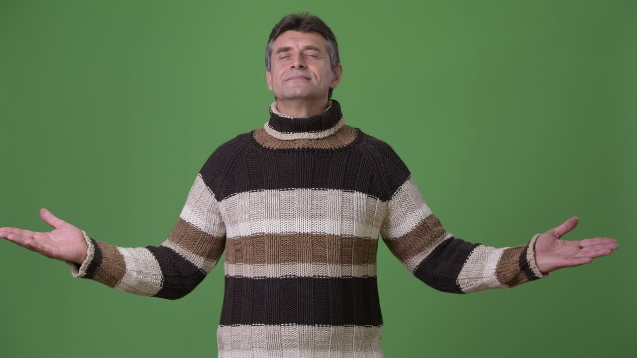 초록색 배경 에 털 목 스웨터 를 입은 성숙 한 잘생긴 남자