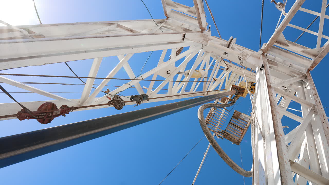 Metal pole rotating attached to the support. Low angle view on the drilling equipment producing gas and oil.
