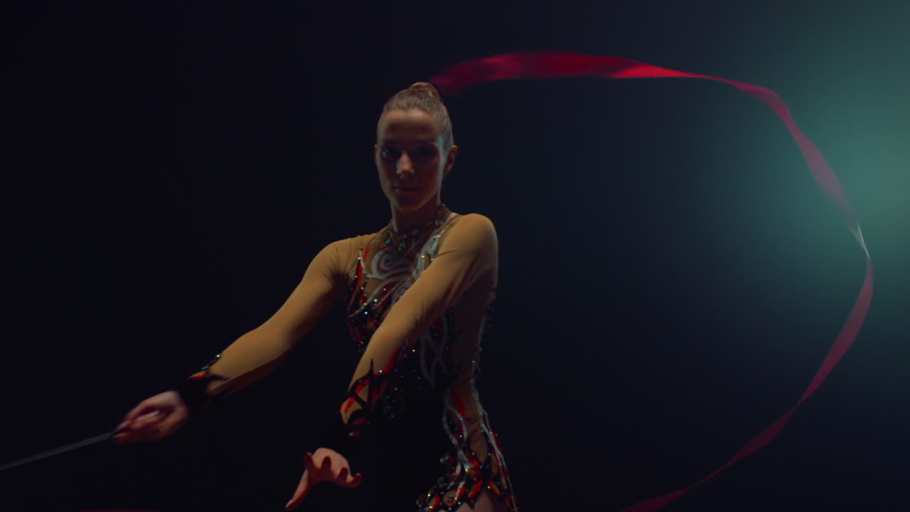 Donna aggraziata che fa ginnastica ritmica. Ginnasta attraente che si esibisce con il nastro.