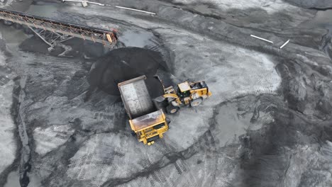 Toma-Aérea-De-Arriba-Hacia-Abajo-De-Un-Camión-Cargando-Granito-En-Un-Camión-Volquete-Durante-El-Día-Soleado-En-La-Mina