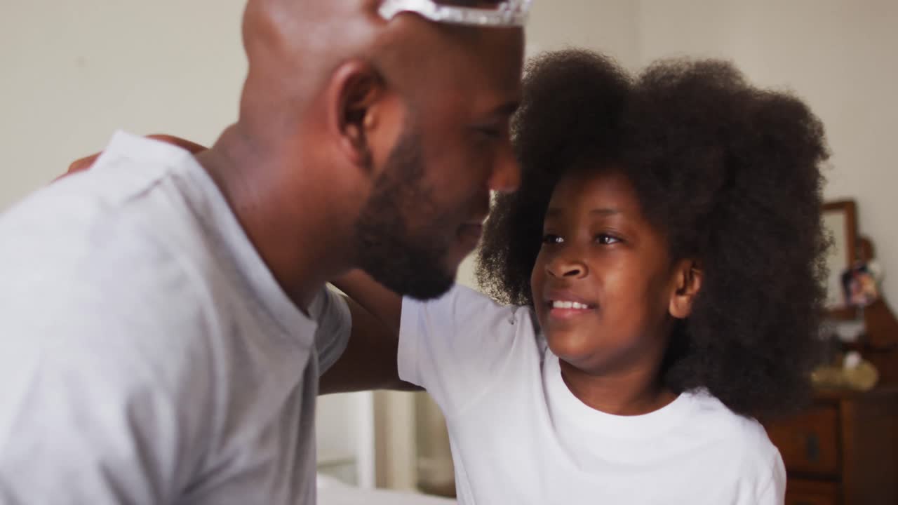 African american daughter and father wearing crown hugging each other at home