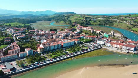 Beautiful-canal-in-Spain,-showing-a-vibrant-touristic-small-city-with-mountains-in-the-back-a-sandbank-and-soil-sedimentation