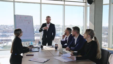 business meeting in the office. manager talks about the curve on the chart. business people discuss the ideas in the big light office.