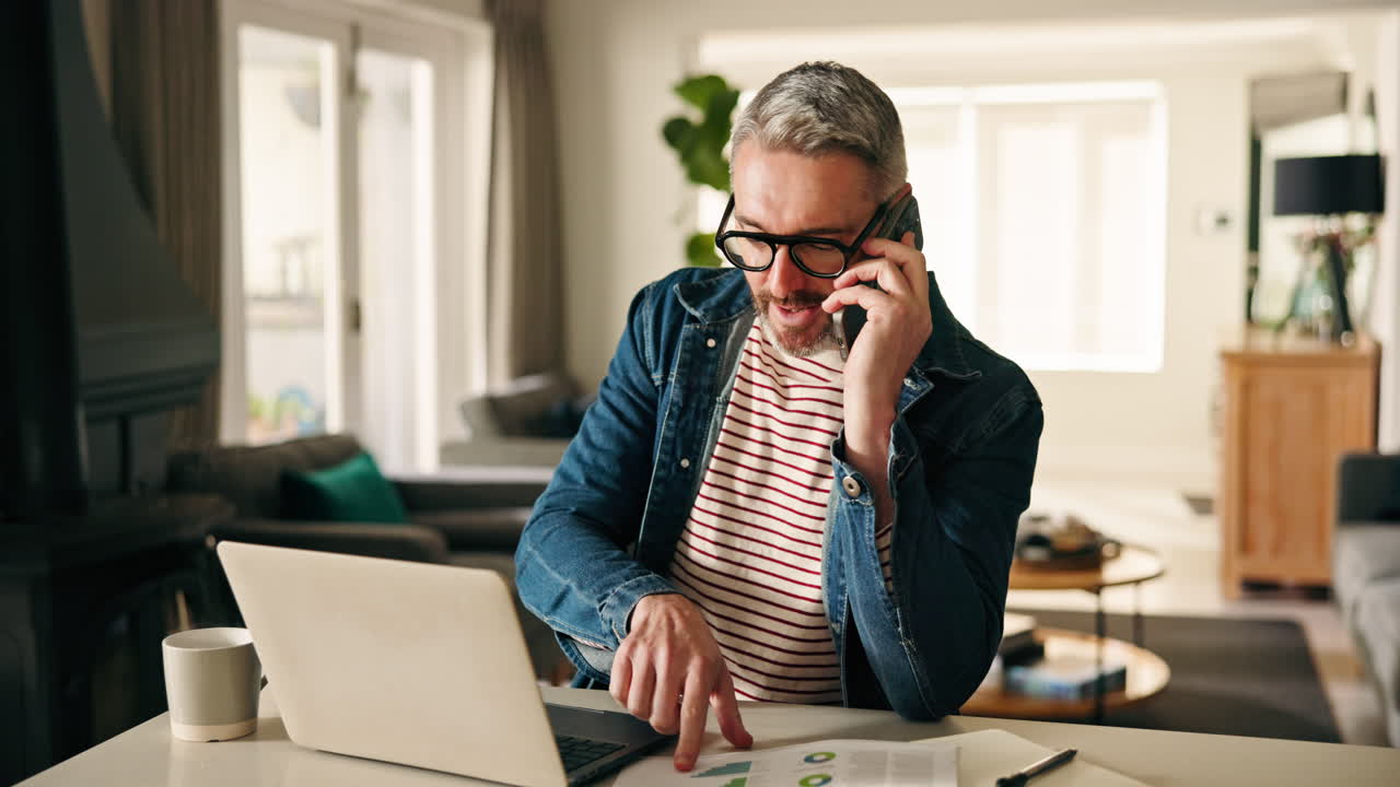 Man Working from Home on Laptop While on a Phone Call