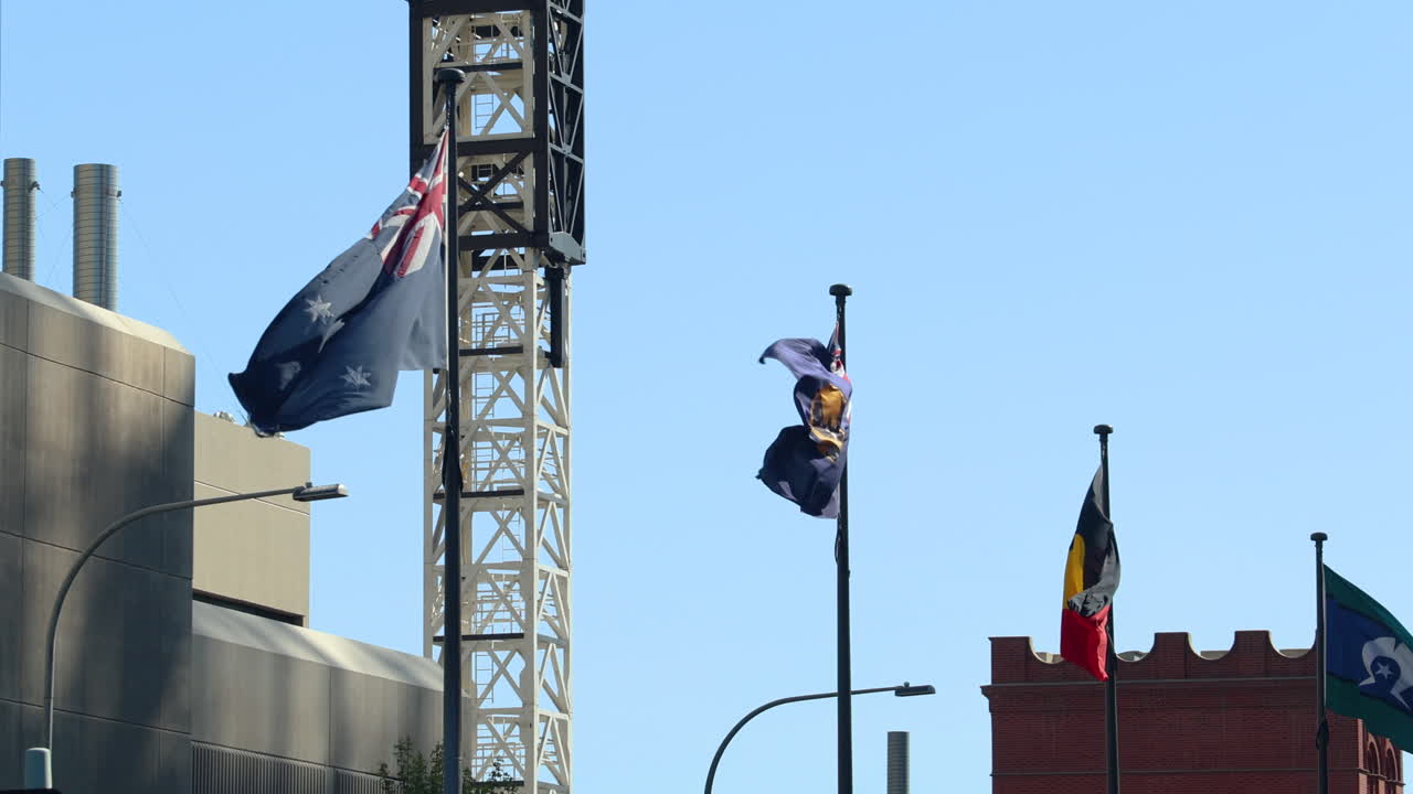 Australian and Aboriginal flags waving in the wind, set against a blue sky. Ideal for projects related to Australia, travel, national identity, or any project relating to Australia Day