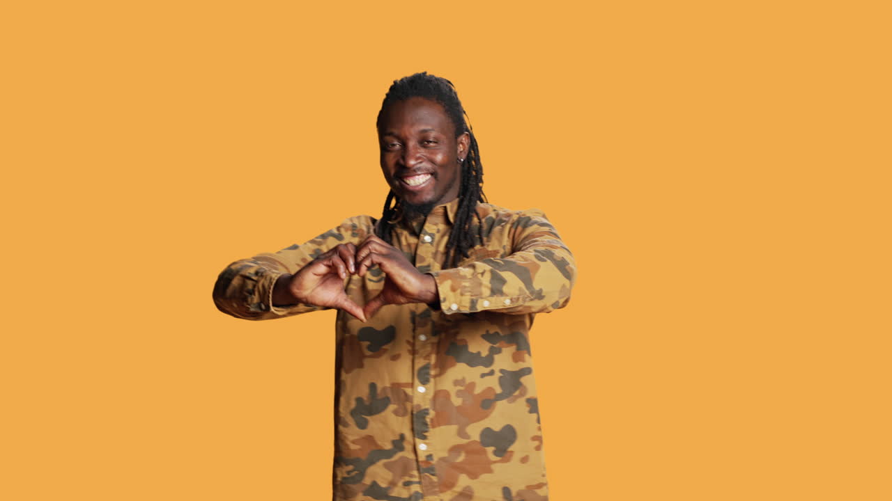 남성 모델이 스튜디오에서 심장 모양의 표지판을 제시합니다.