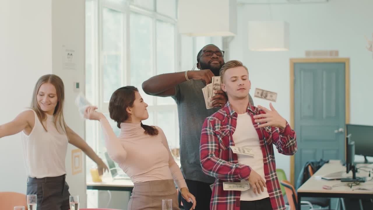 Young people making rain with money at coworking space. Money flying in air.