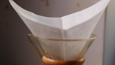 pouring coffee into the filter and glass press for french press coffee preparation caught in front as crushed coffee falls into the filter in slow motion capture at 120 fps