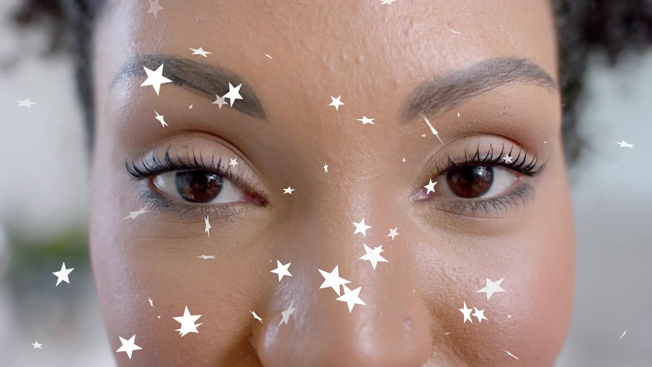 Star graphic flickering across face, woman opening eyes and revealing lashes and makeup for beauty
