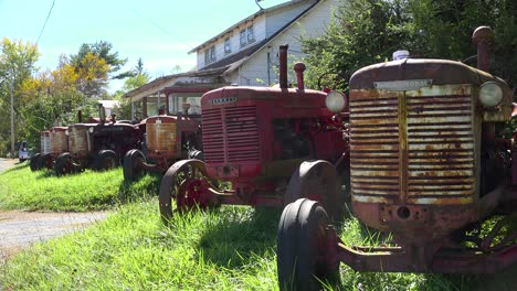 old vintage tractors sit in the front yard of a home in a rural area