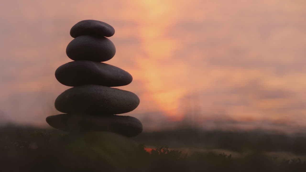 한 손이 돌의 조화와 균형 개념의 탑 위에 돌을 놓는다