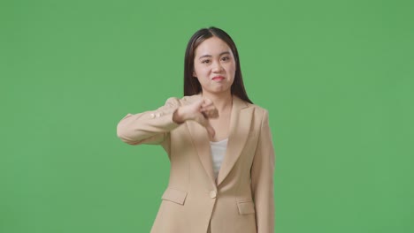 asian business woman showing thumbs down gesture while standing in the green screen studio