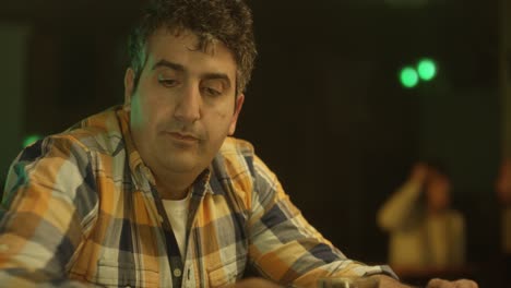 a man sitting at a counter in a relaxed mood and giving expressions of surprise and excitement after reading his messages over phone. static.