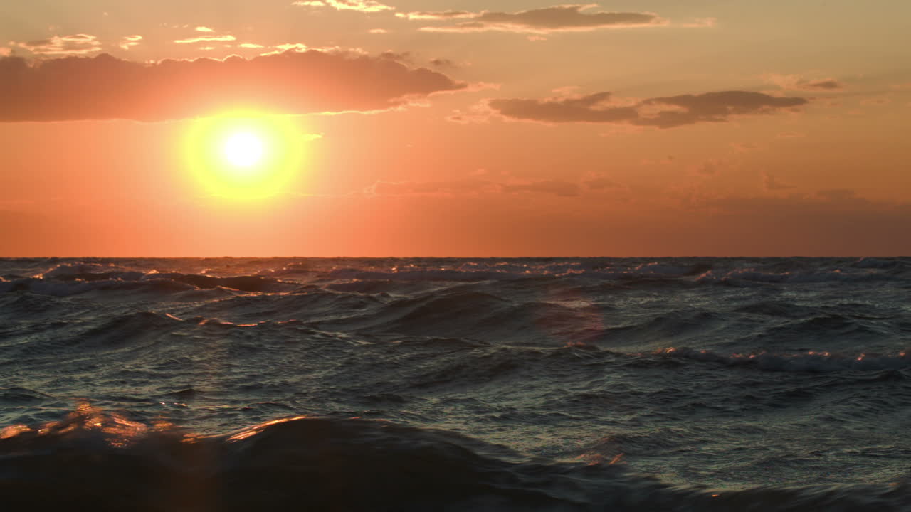 격렬한 바다 위에서 황금빛 해가 지는 것