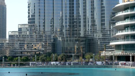 modern glass and concrete building near fountains in sunny day, dubai