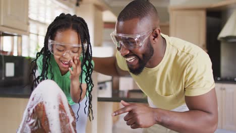 Happy-african-american-father-and-daughter-doing-science-experiments-with-makeshift-volcano