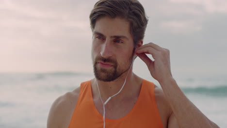 portrait of fit young man puts on earphones enjoying calm relaxed day at beach seaside