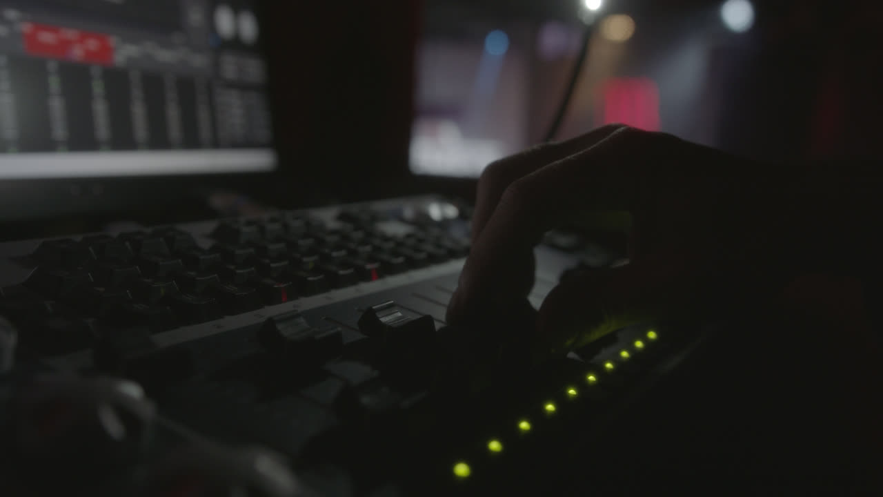 Amazing slow motion shot of the detail of a hand of a live show sound engineer moving a fade of the sound table moving the stage lights